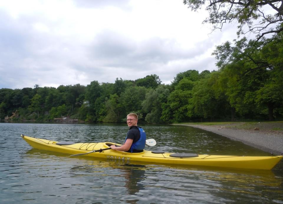 Luke paddling a yellow kayak near a wooded shore