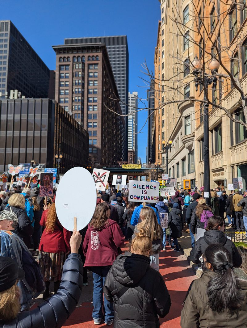 A crowd marching downtown with handmade signs