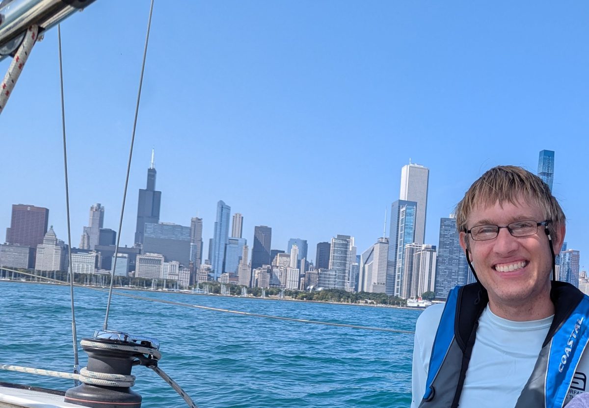 Luke smiling on a sailboat with the Chicago skyline behind him
