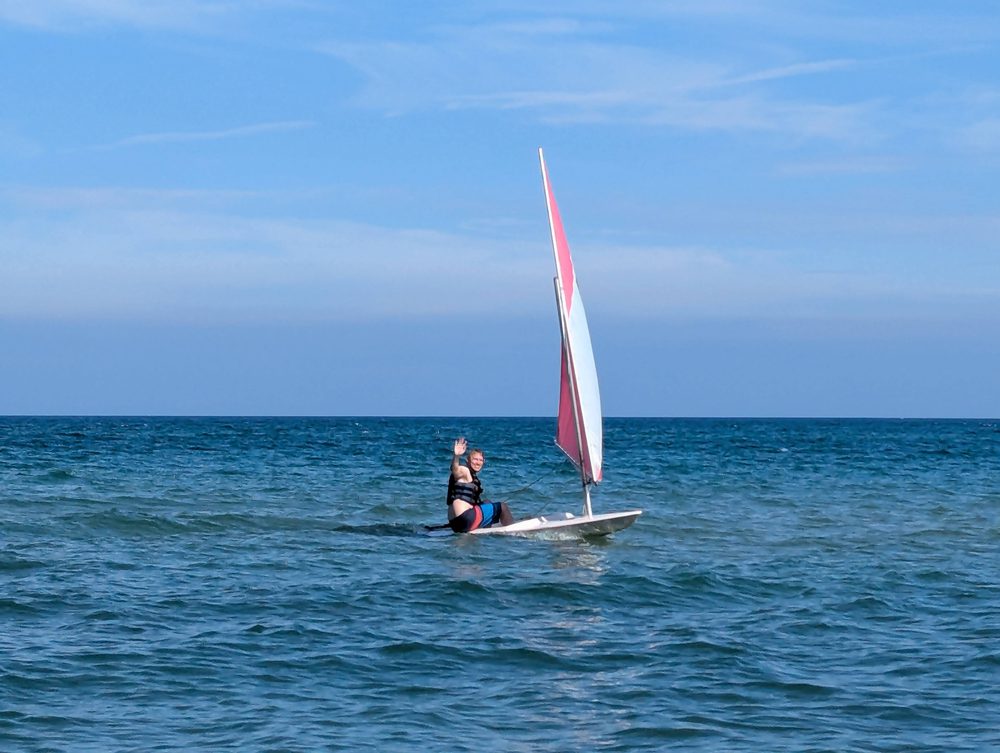 A small sailboat with a red sail on open blue water