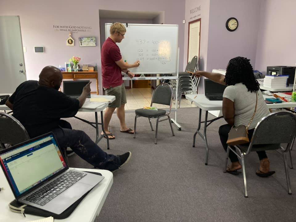 Luke teaching at a whiteboard in a small classroom