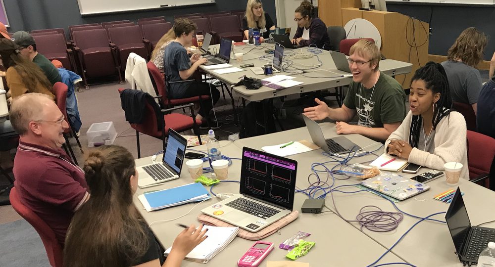 Luke at a table of students working on laptops